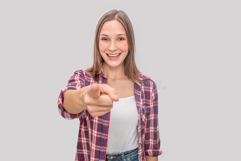 Nette und positive Stände und Punkte der jungen Frau auf Kamera Sie lächelt Modell trägt weißes T-Shirt und Cellohemd lizenzfreies stockfoto Nette und positive Stände und Punkte der jungen Frau auf Kamera Sie lächelt Modell trägt weißes T-Shirt und Cellohemd lizenzfreies stockfoto