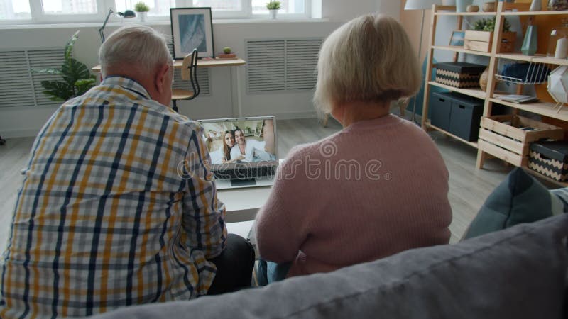 Nette ältere Menschen, die mit den jungen Paaren zu Hause machen Videokonferenz mit Notebook sprechen
