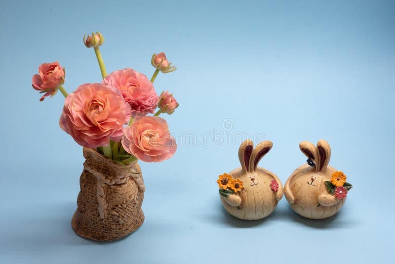 Netter Blumenstrauß von empfindlichen rosa Butterblumeen und von Hasefigürchen auf einem blauen Hintergrund lizenzfreie stockfotos Netter Blumenstrauß von empfindlichen rosa Butterblumeen und von Hasefigürchen auf einem blauen Hintergrund lizenzfreie stockfotos