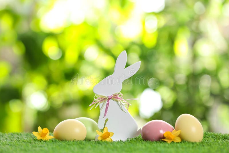Netter hölzerner Osterhase und gefärbte Eier auf Gras gegen unscharfen Hintergrund stockbilder