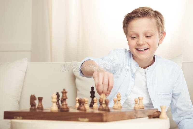 Netter kleiner Junge, der zu Hause Schach allein spielt stockbild Netter kleiner Junge, der zu Hause Schach allein spielt stockbild