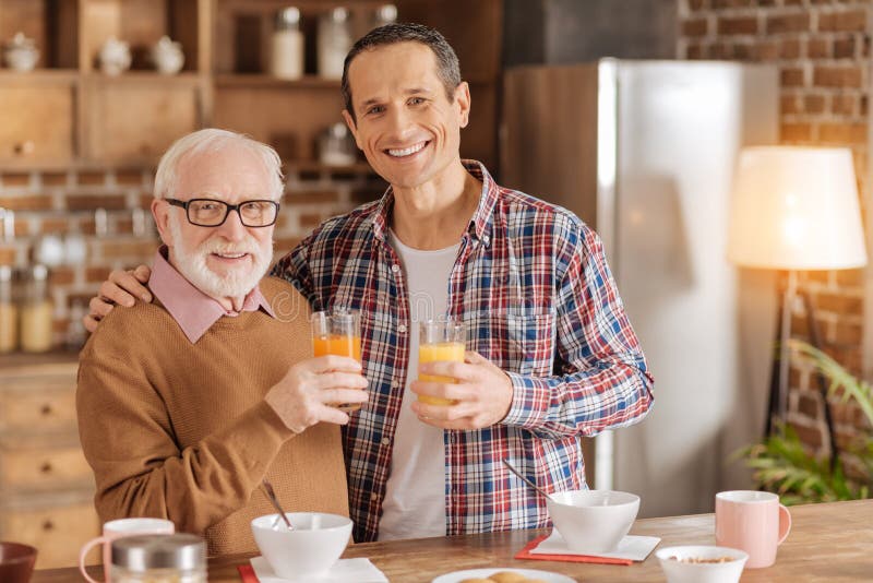 Netter Vater und Sohn, die mit Gläsern Saft aufwirft stockbild Netter Vater und Sohn, die mit Gläsern Saft aufwirft stockbild
