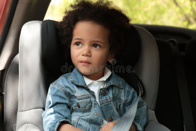 Nettes afro-amerikanisches Kind, das im Sicherheitssitz sitzt Gefahrenverhinderung stockfotografie Nettes afro-amerikanisches Kind, das im Sicherheitssitz sitzt Gefahrenverhinderung stockfotografie