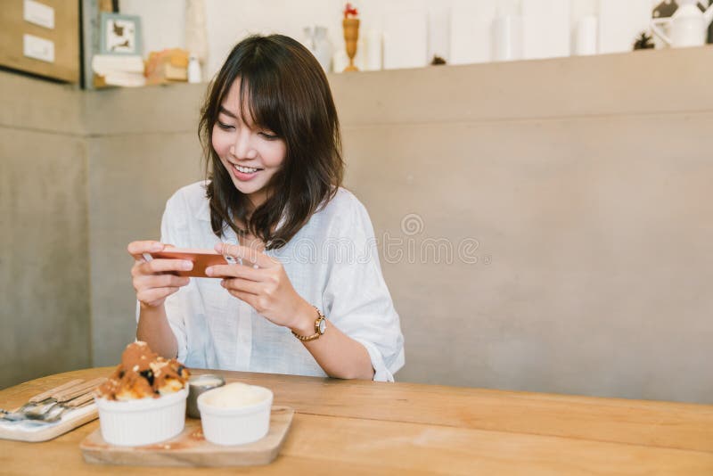 Nettes asiatisches Mädchen, das Foto des Nachtischs an der Kaffeestube macht Freizeitbetätigung oder Handyphotographie, Lebensmit lizenzfreie stockbilder Nettes asiatisches Mädchen, das Foto des Nachtischs an der Kaffeestube macht Freizeitbetätigung oder Handyphotographie, Lebensmit lizenzfreie stockbilder