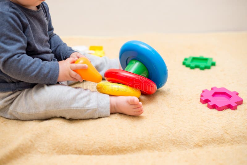 Nettes Baby, das mit bunter Spielzeugpyramide im hellen Schlafzimmer spielt Spielwaren f?r Kleinkinder Kind mit p?dagogischem Spi lizenzfreie stockfotografie Nettes Baby, das mit bunter Spielzeugpyramide im hellen Schlafzimmer spielt Spielwaren f?r Kleinkinder Kind mit p?dagogischem Spi lizenzfreie stockfotografie