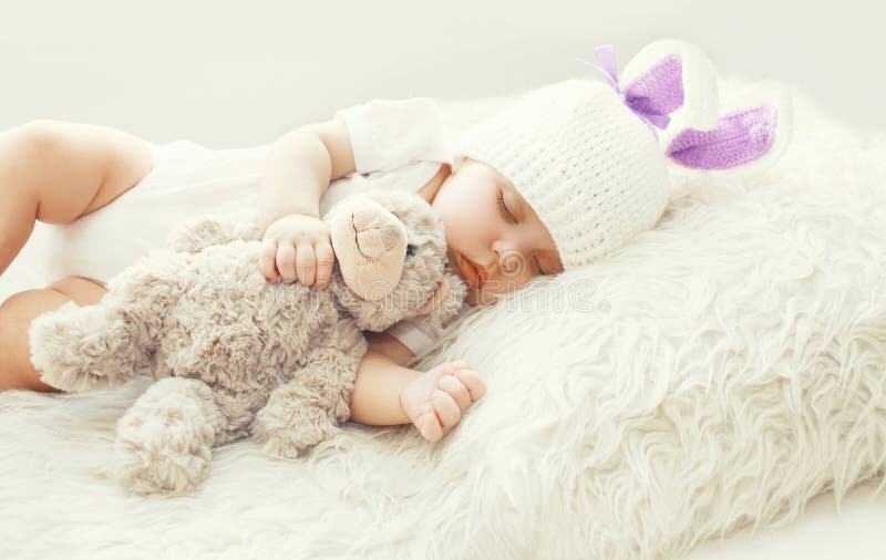 Nettes Baby, das mit Teddybärspielzeug auf weißem weichem Betthaus schläft lizenzfreie stockfotos Nettes Baby, das mit Teddybärspielzeug auf weißem weichem Betthaus schläft lizenzfreie stockfotos