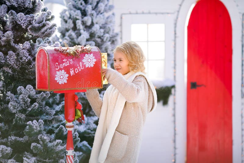 Nettes blondes gelocktes Mädchen mit Buchstaben nahe dem Sankt-` s Briefkasten lizenzfreie stockfotos Nettes blondes gelocktes Mädchen mit Buchstaben nahe dem Sankt-` s Briefkasten lizenzfreie stockfotos