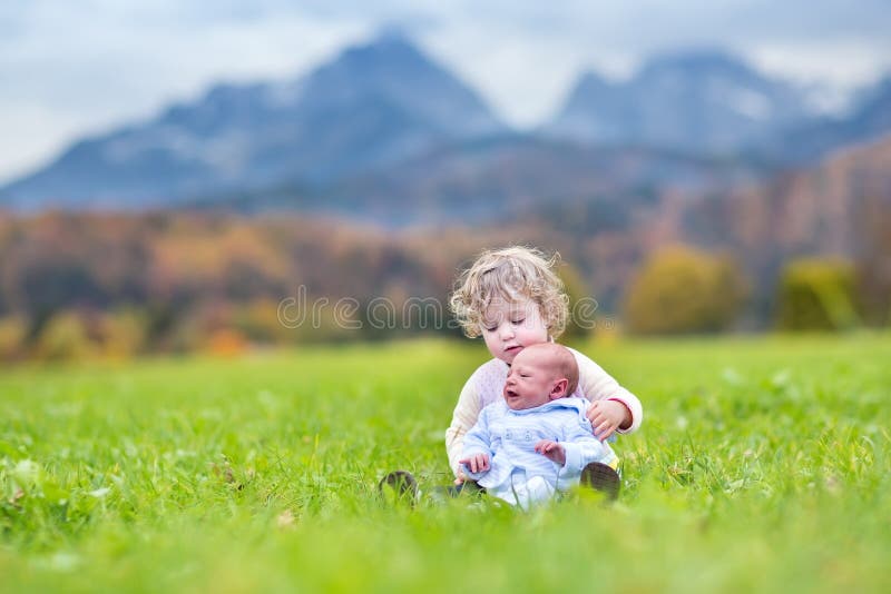 Nettes gelocktes Kleinkindmädchen und ihr neugeborener Babybruder, die herein spielt lizenzfreie stockfotografie Nettes gelocktes Kleinkindmädchen und ihr neugeborener Babybruder, die herein spielt lizenzfreie stockfotografie