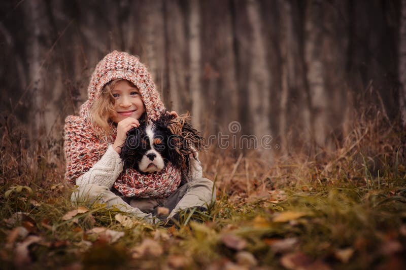 Nettes glückliches Kindermädchen mit ihrem Hund auf gemütlichem Herbstweg im Wald lizenzfreies stockfoto