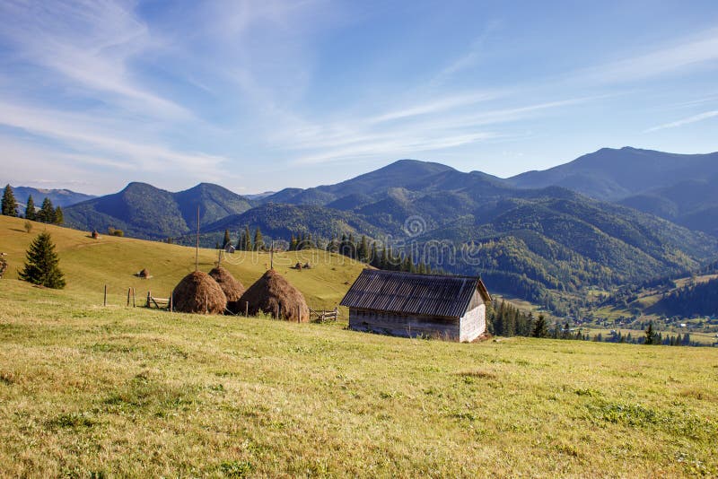 Nettes Holzhaus und erntet auf Gebirgshintergrund lizenzfreie stockfotos