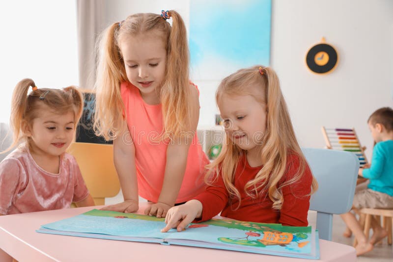 Nettes kleine Kinderlesebuch zusammen bei Tisch zuhause lizenzfreies stockbild Nettes kleine Kinderlesebuch zusammen bei Tisch zuhause lizenzfreies stockbild