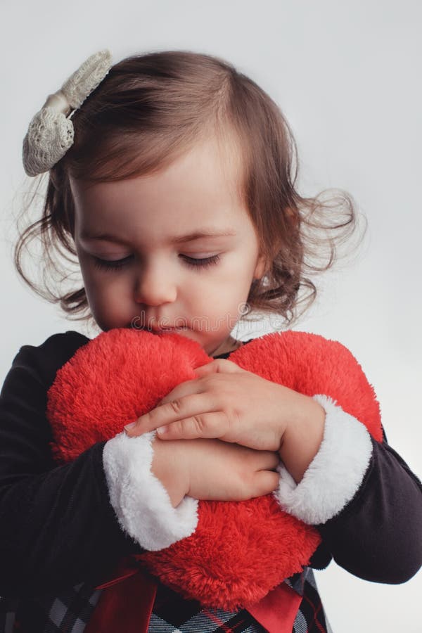 Nettes kleines Kindermädchenporträt, das rotes Herzspielzeug auf weißem b hält stockfoto Nettes kleines Kindermädchenporträt, das rotes Herzspielzeug auf weißem b hält stockfoto