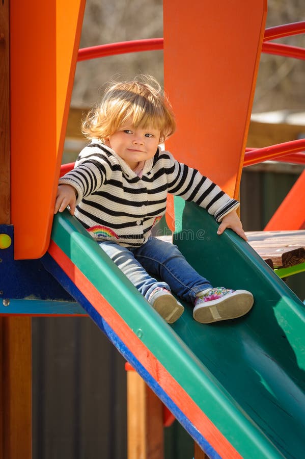 Nettes kleines Kleinkindmädchen, welches unten das Dia der Kinder schiebt lizenzfreie stockfotos Nettes kleines Kleinkindmädchen, welches unten das Dia der Kinder schiebt lizenzfreie stockfotos
