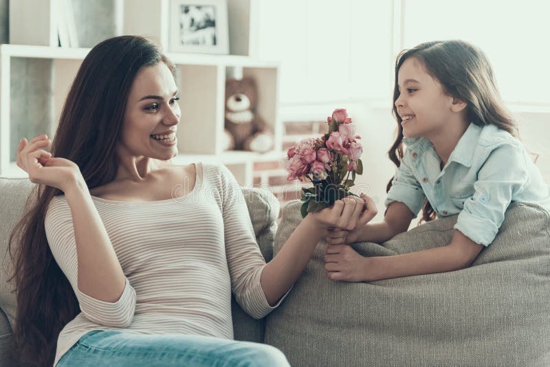 Nettes kleines Mädchen, das der jungen Frau Blumen gibt lizenzfreie stockbilder Nettes kleines Mädchen, das der jungen Frau Blumen gibt lizenzfreie stockbilder
