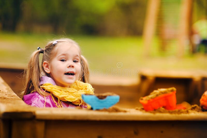 Nettes kleines Mädchen, das in einem Sandkasten spielt stockbilder Nettes kleines Mädchen, das in einem Sandkasten spielt stockbilder