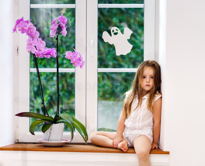 Nettes kleines Mädchen mit der Blume, die auf Fensterbrett von neuen PVC wi sitzt lizenzfreies stockbild Nettes kleines Mädchen mit der Blume, die auf Fensterbrett von neuen PVC wi sitzt lizenzfreies stockbild