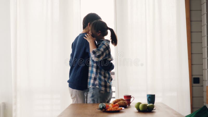 Nettes Mädchen und Kerl trinken Tee in der Küche, die dann nach dem Frühstück tanzt und küsst, das Gefühle und das Genießen ausdr