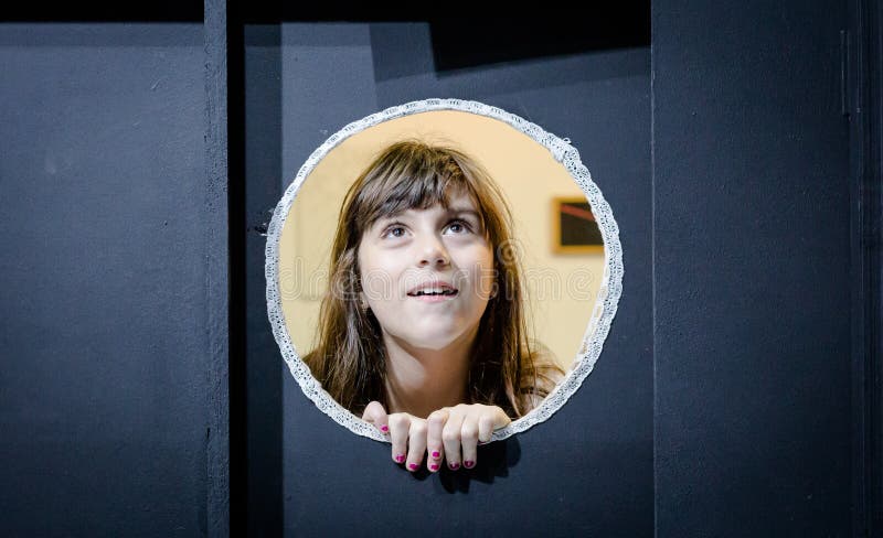 Nettes Mädchen auf Rundschreiben gestaltetem Fenster stockfoto Nettes Mädchen auf Rundschreiben gestaltetem Fenster stockfoto
