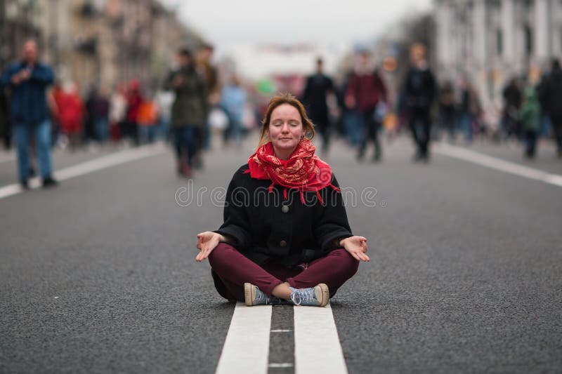 Nettes Mädchen, das in der Meditation mitten in einer verkehrsreichen Straße sitzt