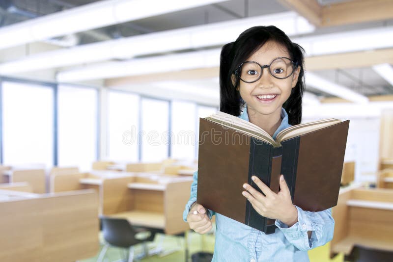 Nettes Mädchen hält Buch im Klassenzimmer lizenzfreies stockfoto Nettes Mädchen hält Buch im Klassenzimmer lizenzfreies stockfoto