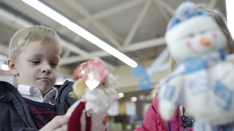 Nettes Mädchen und Junge, die mit Weihnachtsspielwaren im Einkaufszentrum spielt Langsame Bewegung