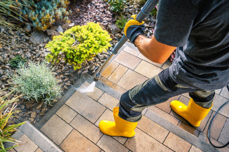 Nettoyage des marches extérieures avec une lave-pression dans des bottes jaune vif photos libres de droits