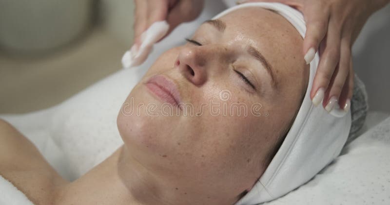 Nettoyage du visage avec le tissu au salon de beauté banque de vidéos