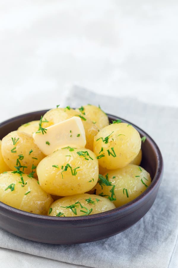 Neue junge gekochte Kartoffel überstiegen mit geschmolzener Butter und gehacktem Dill, in der keramischen Schüssel, Vertikale, Ko lizenzfreie stockfotografie Neue junge gekochte Kartoffel überstiegen mit geschmolzener Butter und gehacktem Dill, in der keramischen Schüssel, Vertikale, Ko lizenzfreie stockfotografie
