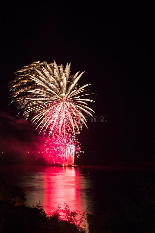 Neues Jahr ` s Eve Fireworks startete vom Wasser mit Reflexionen stockbild Neues Jahr ` s Eve Fireworks startete vom Wasser mit Reflexionen stockbild