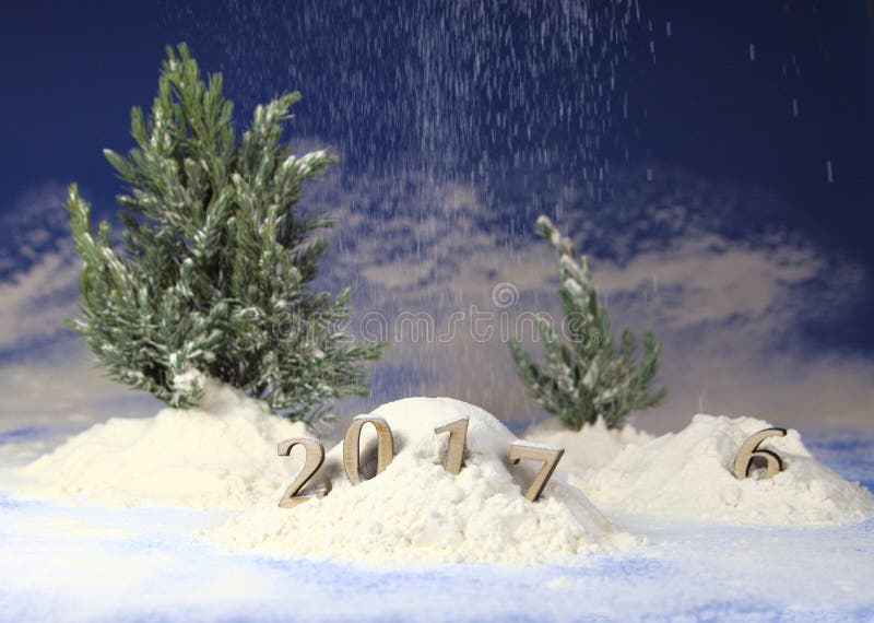 Snowdrift in the forest with figures of the coming new year 2017 against the background of snowfall and fir-trees. Snowdrift in the forest with figures of the coming new year 2017 against the background of snowfall and fir-trees