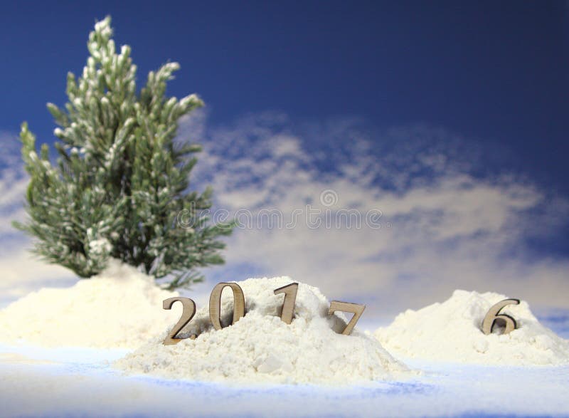 Snowdrift in the forest with figures of the coming new year 2017 against the background of snowfall and fir-trees. Snowdrift in the forest with figures of the coming new year 2017 against the background of snowfall and fir-trees