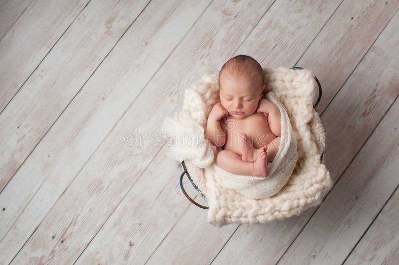 Neugeborenes Baby, das in einem Draht-Korb schläft
