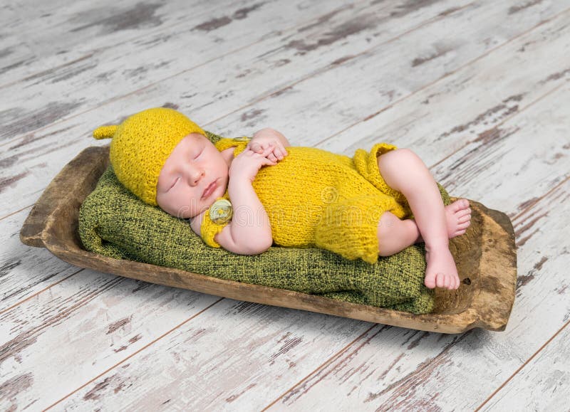 Neugeborenes Baby im gelben Kostüm schlafend auf hölzernem Feldbett stockfotografie Neugeborenes Baby im gelben Kostüm schlafend auf hölzernem Feldbett stockfotografie