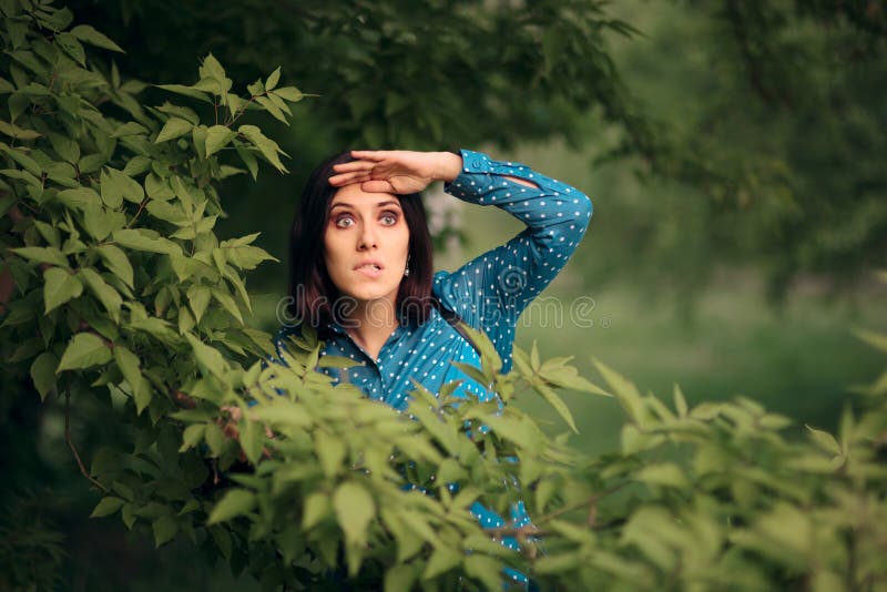 Neugierige eifersüchtige Frau, die von den Büschen ausspioniert stockbild Neugierige eifersüchtige Frau, die von den Büschen ausspioniert stockbild