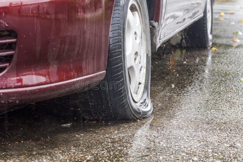 Neumático desinflado del coche en día lluvioso