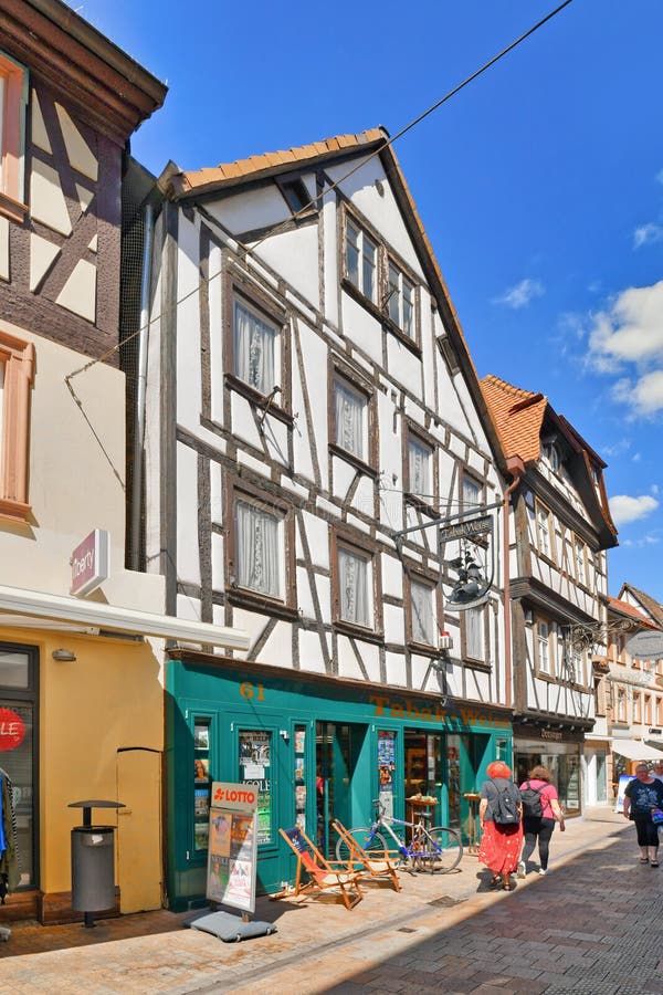 Neustadt an der Weinstrasse, Germany - August 2022: Old timber-framed house in historic city center with small shops on sunny day. Neustadt an der Weinstrasse, Germany - August 2022: Old timber-framed house in historic city center with small shops on sunny day