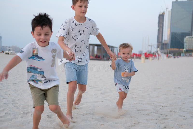 Three brothers are running on the beach, holding hands royalty free stock images Three brothers are running on the beach, holding hands royalty free stock images