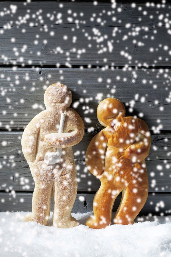 Nevadas con los hombres de pan de jengibre de la Navidad en el montón de la nieve contra fondo de madera imagen de archivo Nevadas con los hombres de pan de jengibre de la Navidad en el montón de la nieve contra fondo de madera imagen de archivo