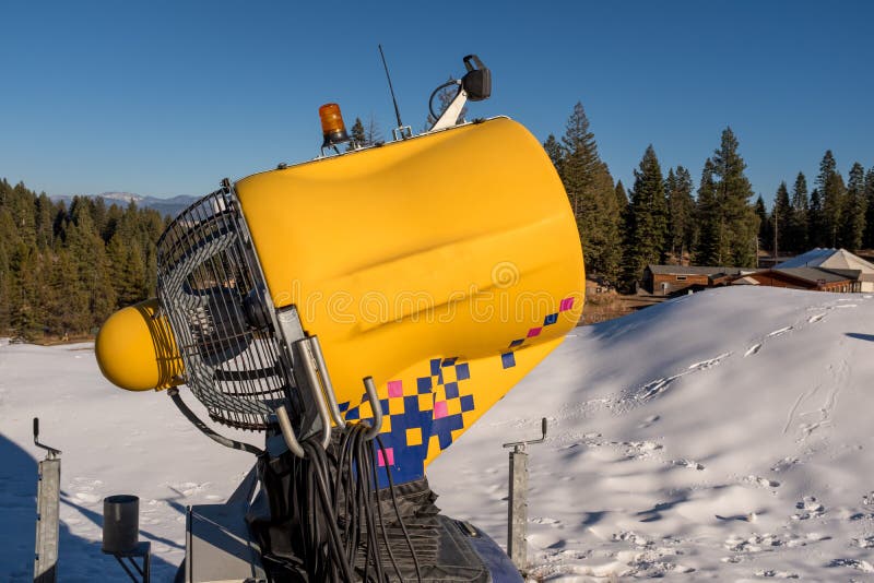 Neve que faz a máquina em uma estância de esqui local com floresta verde e imagem de stock Neve que faz a máquina em uma estância de esqui local com floresta verde e imagem de stock