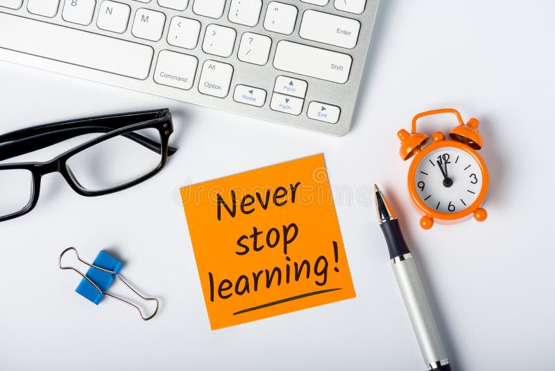 Never stop Learning - written message on white desk workplace. E-learning education concept