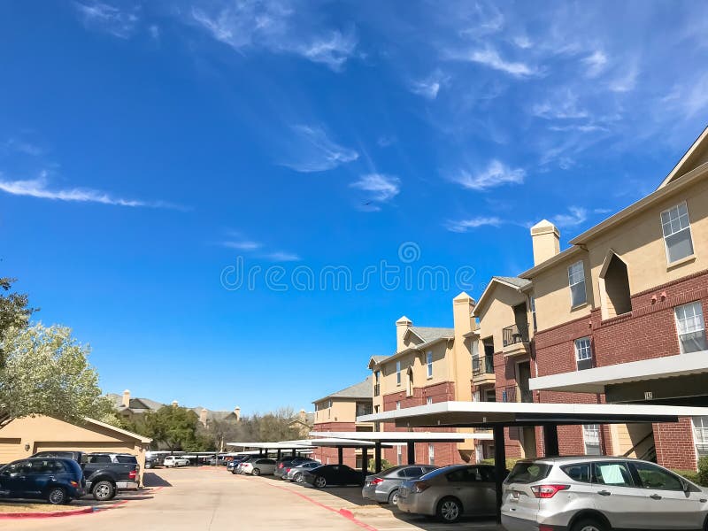 New Apartment Complex with Covered Parking Under Sunny Cloud Sky in
