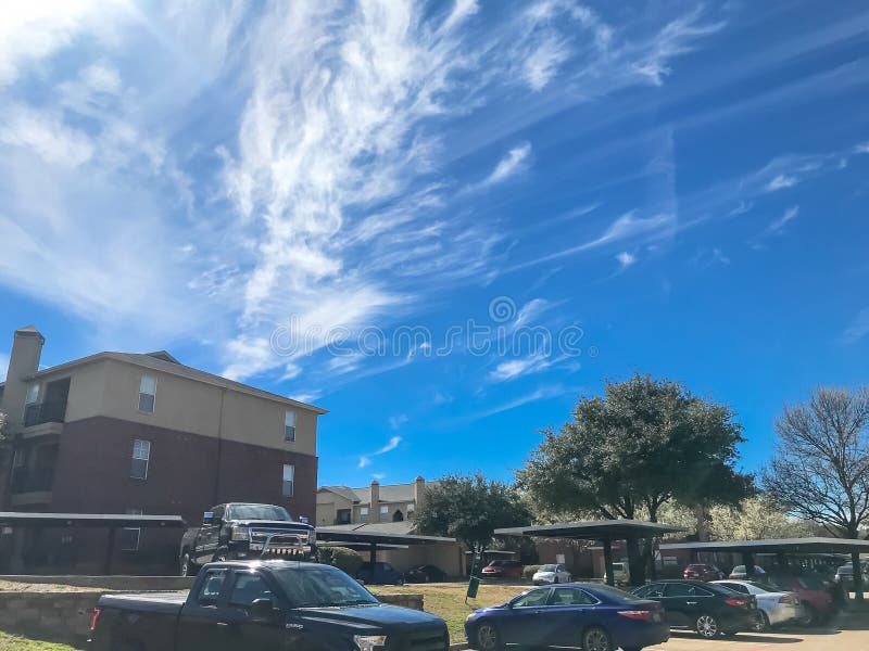 New Apartment Complex with Covered Parking Under Sunny Cloud Sky in