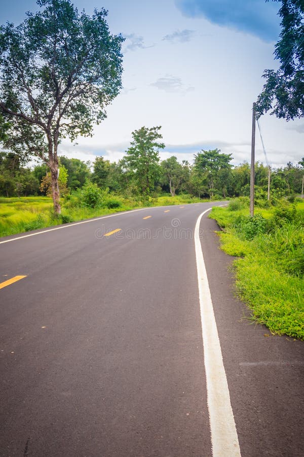 New asphalt winding curve road in the countryside with perspective white line and cloudy blue sky background.