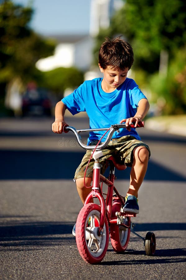 A young boy learning how to ride a bicycle on the street. A young boy learning how to ride a bicycle on the street