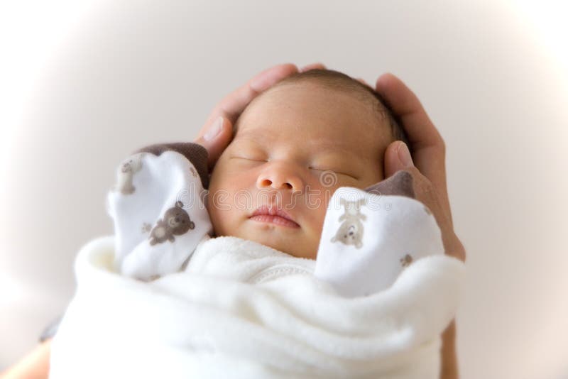 Appena nato, il bambino dorme nella mani di suo padre.