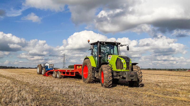 A Claas 630 tractor pulling a trailer to load vintage tractor royalty free stock images