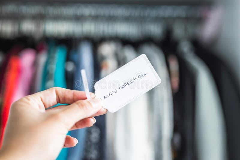 Fashion brands and competition, New Collection sign held in front of rack full of clothes stock images Fashion brands and competition, New Collection sign held in front of rack full of clothes stock images