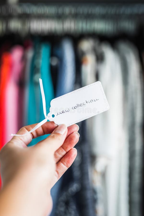 Fashion brands and competition, New Collection sign held in front of rack full of clothes royalty free stock image Fashion brands and competition, New Collection sign held in front of rack full of clothes royalty free stock image