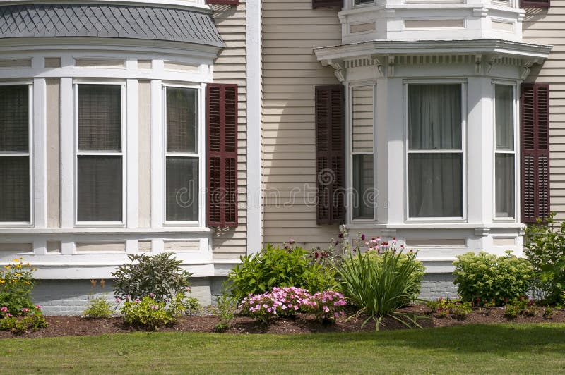 An old New England house with bay windows and bow windows, and flowers for landscaping. An old New England house with bay windows and bow windows, and flowers for landscaping.