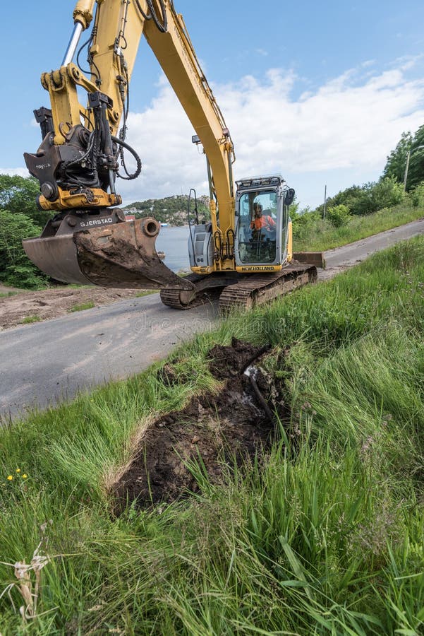 A New Holland excavator digging a ditch.. stock image